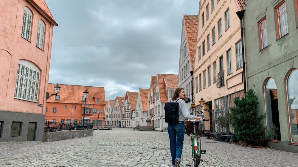 Tjej som leder sin cykel på kullerstensgata i Jakriborg