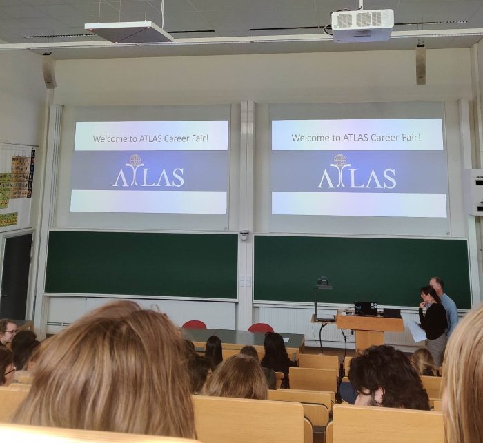 Flera bakhuvuden syns framför en presentation om ATLAS.  