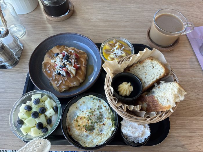 Bild på brunch (bröd, fruktsallad, ägg med avokado, pannkakor och kaffe)