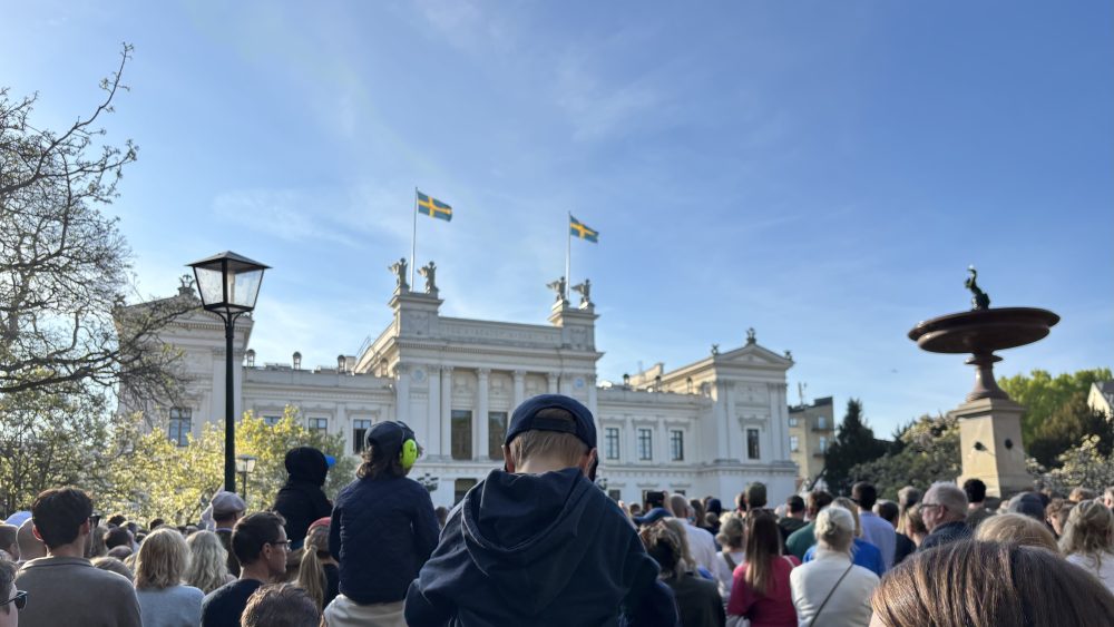 Publik framför Universitetshuset som lyssnar på Studentsångarna.
