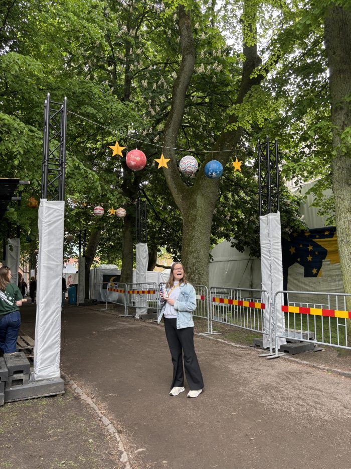 En kompis som står framför en gång på Lundakarnevalen med planetdekorationer som hänger ner.